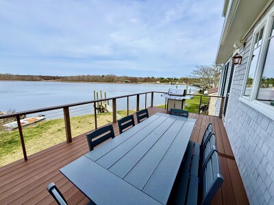 Waterfront deck with outdoor dining, grill, and serene water views