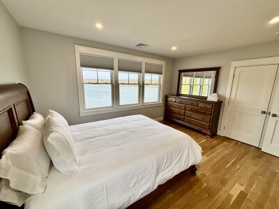 Bright bedroom with water views, hardwood floors, and classic furnishings