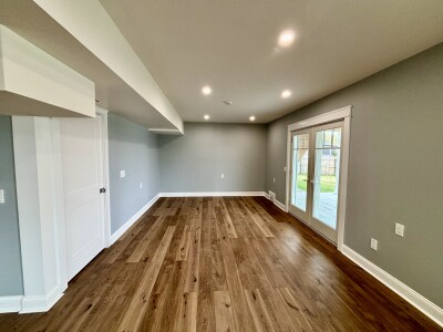 Bright lower-level lounge with wood floors and patio access