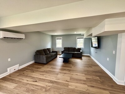 Spacious modern lounge with comfy seating, TV, and wood-look floors