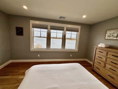 Peaceful bedroom with waterfront views and warm, modern finishes