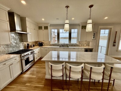 Bright waterfront kitchen with marble island, seating, and stunning views