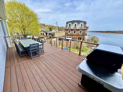 Spacious waterfront deck with outdoor dining, grill, and serene views