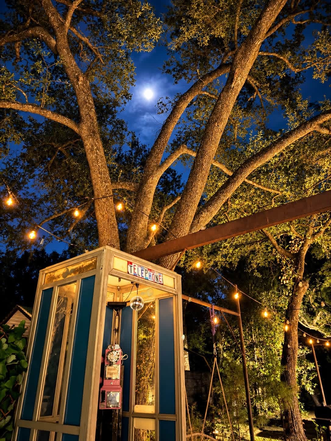Whimsical outdoor nook with string lights and vintage phone booth