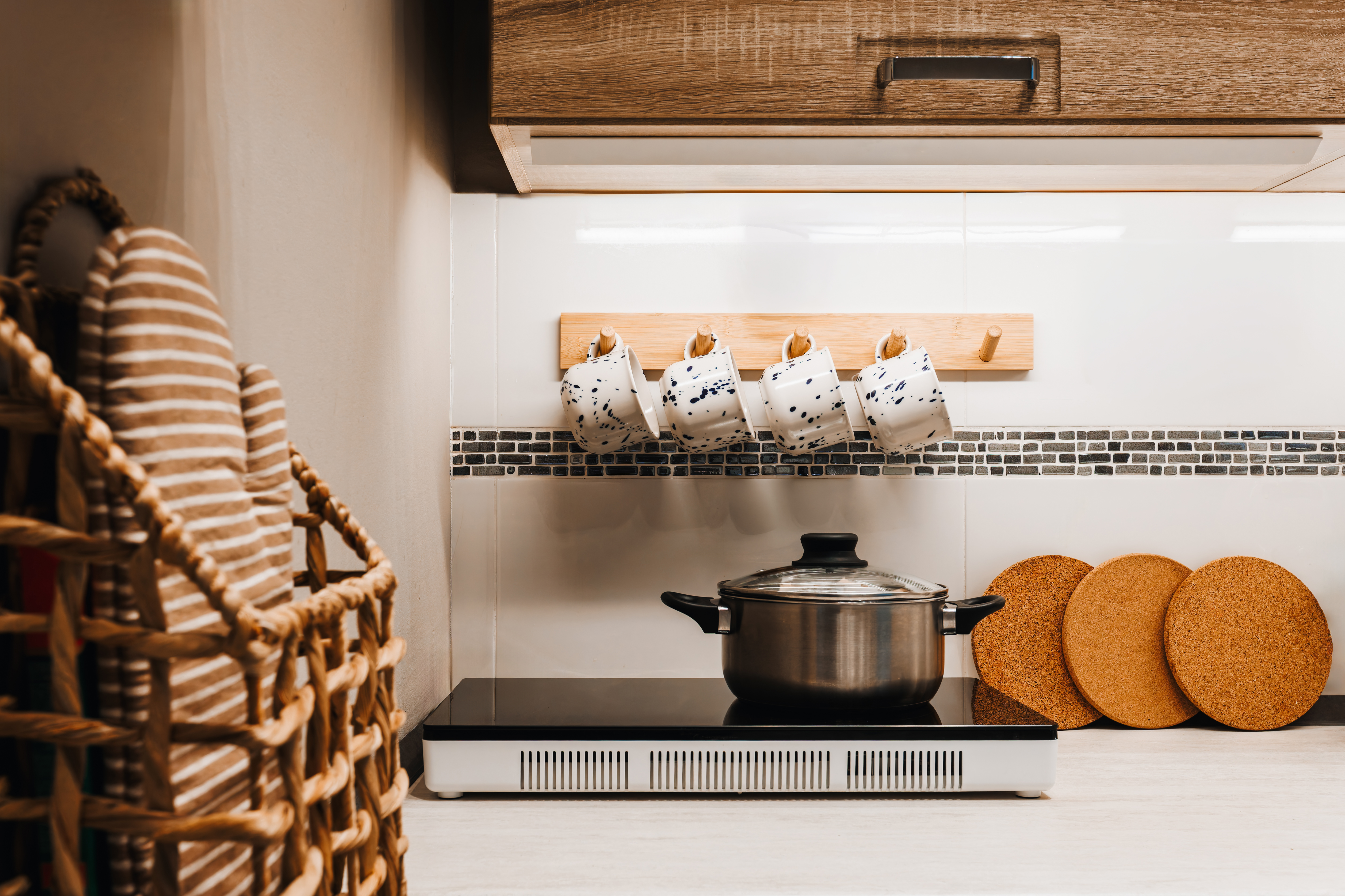 Cozy kitchen corner with cooktop, hanging mugs, and warm rustic touches