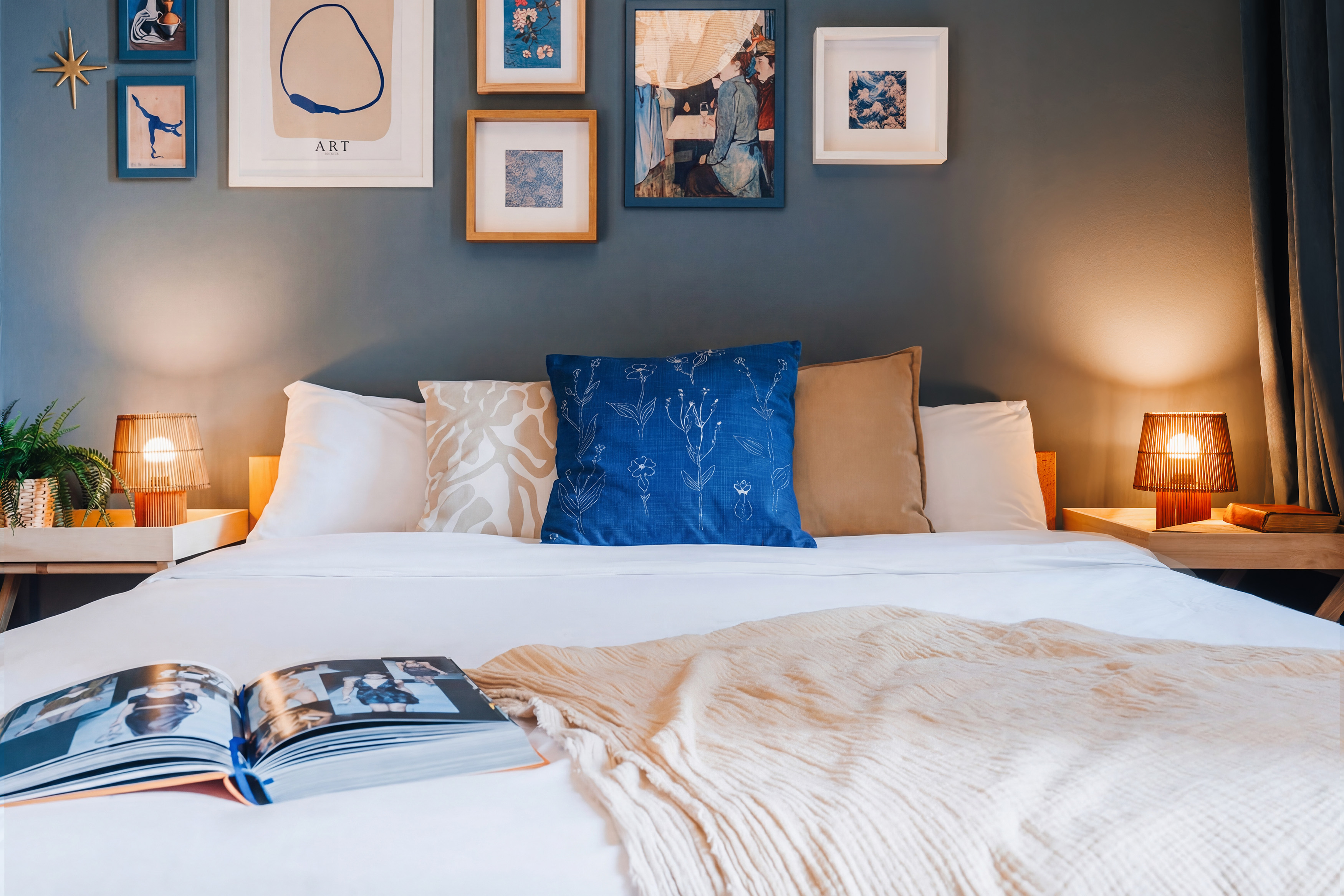 Cozy designer bedroom with gallery wall and warm bedside lighting