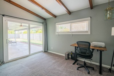 Dedicated Remote Workspace! ‍ This bright area features a standing desk with an ergonomic chair, perfect for remote work. Vaulted ceilings with exposed beams add style. Large sliding glass doors provide direct backyard access for easy breaks.