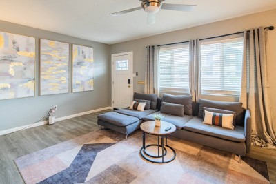 Stylish & Cozy Living Room! ️✨ Relax on the oversized chaise sectional sofa with a modern, low-profile design. The room features a stunning art display with gold accents, luxury vinyl plank flooring, and a ceiling fan for comfort. 