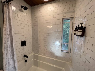 The bathtub in the guest bath has a tile surround an a window.  It may seem weird to have the window there...b