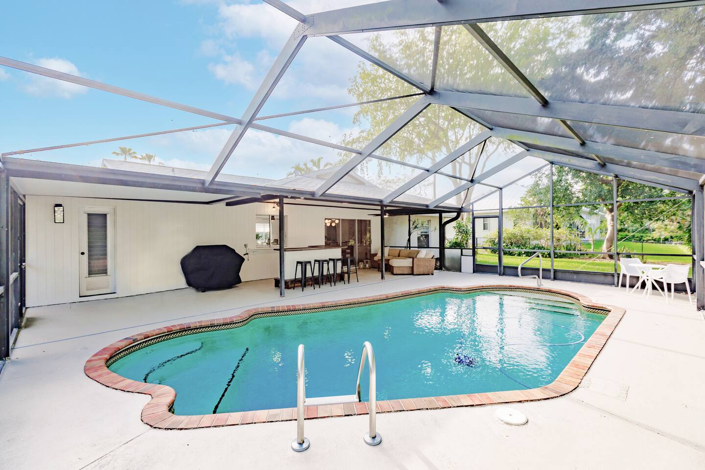 Pool with bar area, propane grill, lounge area, additional seating and covered lanai.