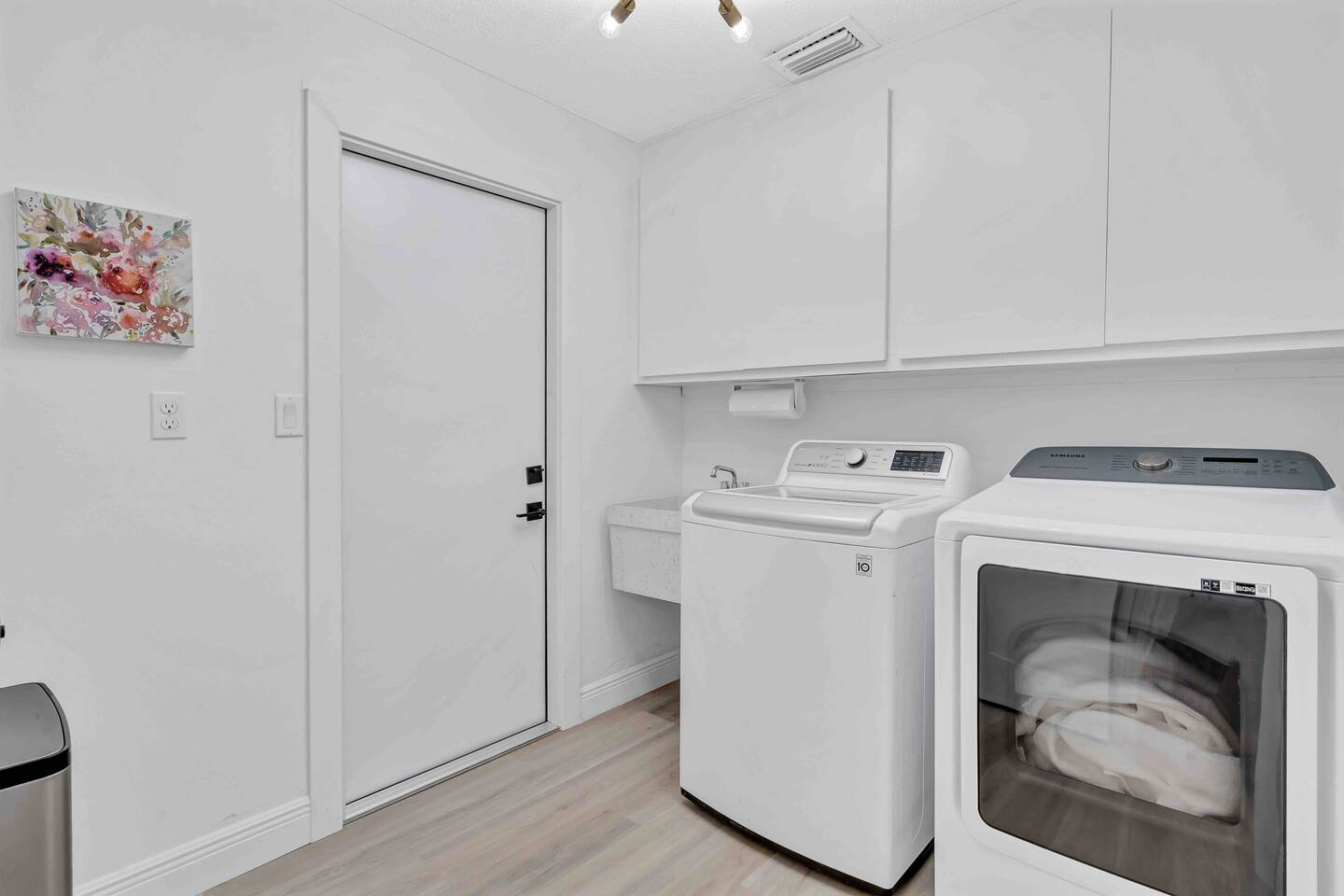 Laundry room with HE washer and dryer, iron, ironing board and utility sink.