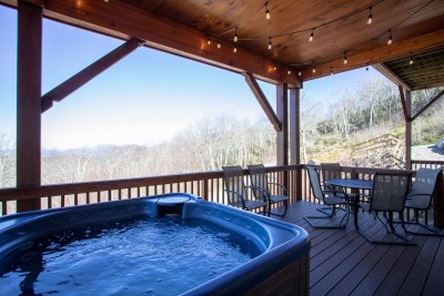 Soak in the private hot tub while taking in peaceful mountain views. With string lights overhead and plenty of seating, this covered deck is perfect for unwinding day or night.