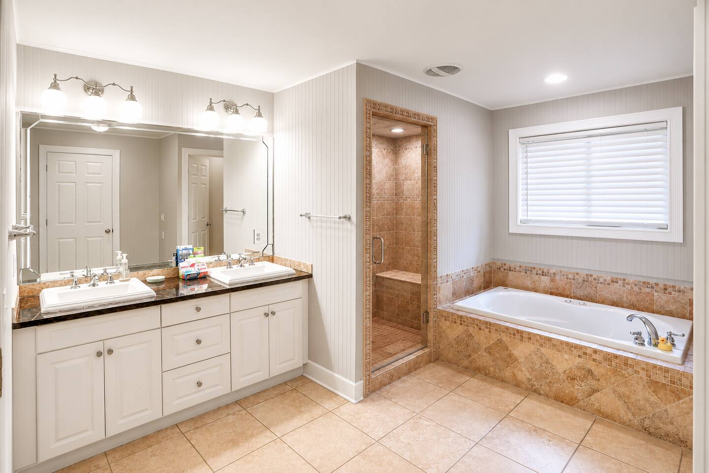 Unwind in the spacious primary bathroom featuring dual vanities, a soaking tub, and a walk-in shower with a built-in bench—perfect for relaxing after a day of adventure.