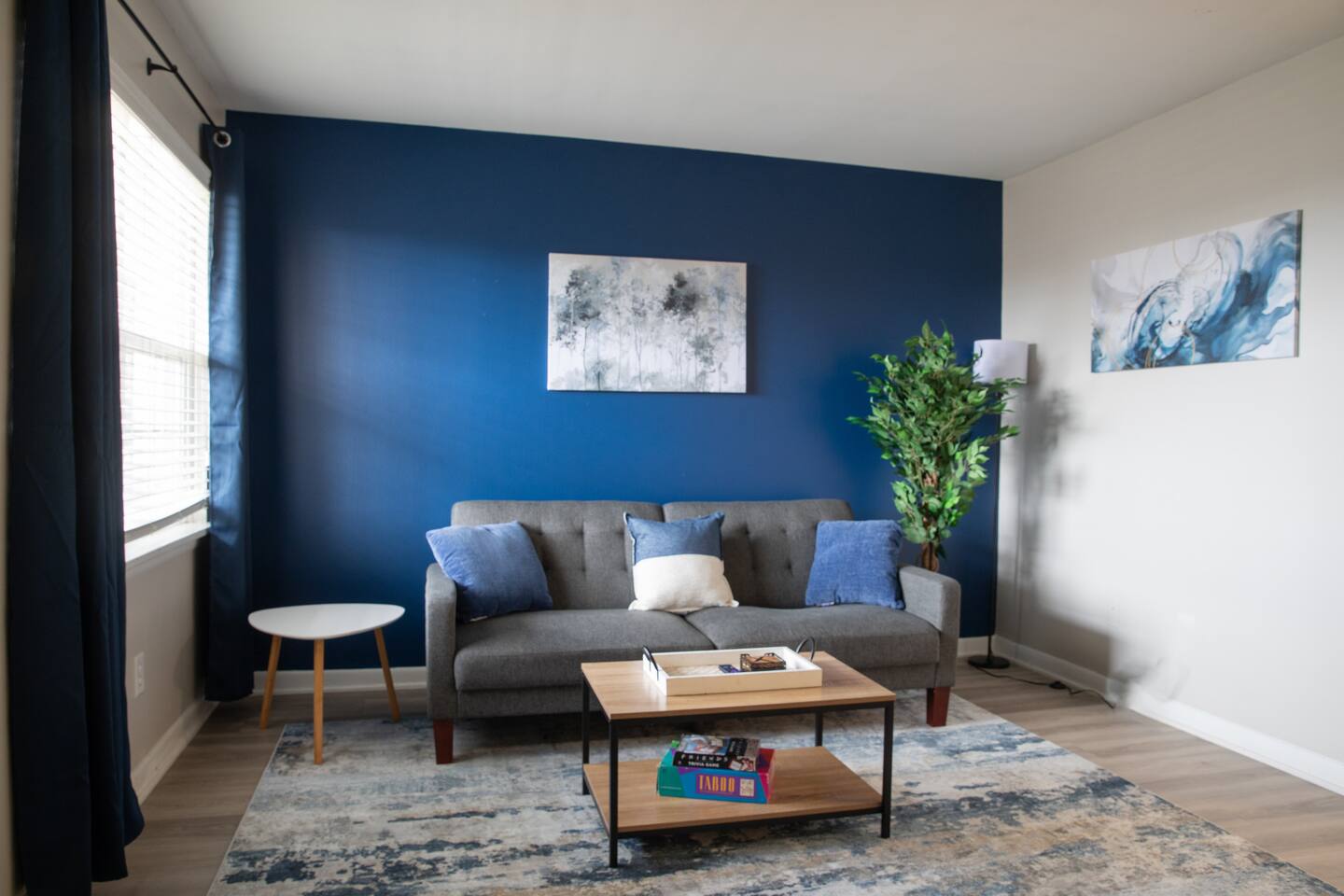 Modern living room with bold blue accent wall, cozy seating, and a bright, inviting atmosphere.