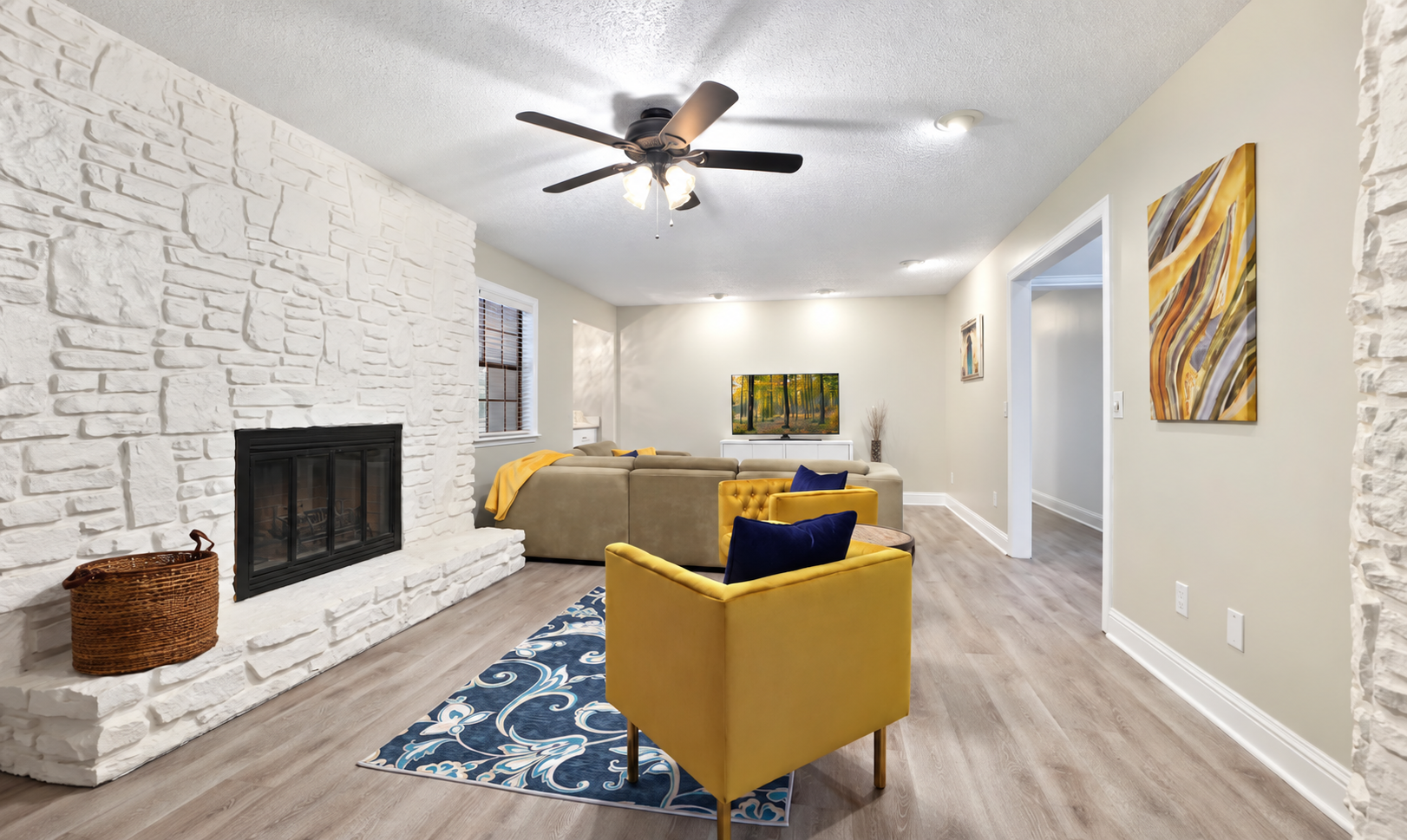 Comfortable lounge seating beside the stone fireplace, with the living-room sectional and Smart TV beyond. The fireplace is currently non-operational.