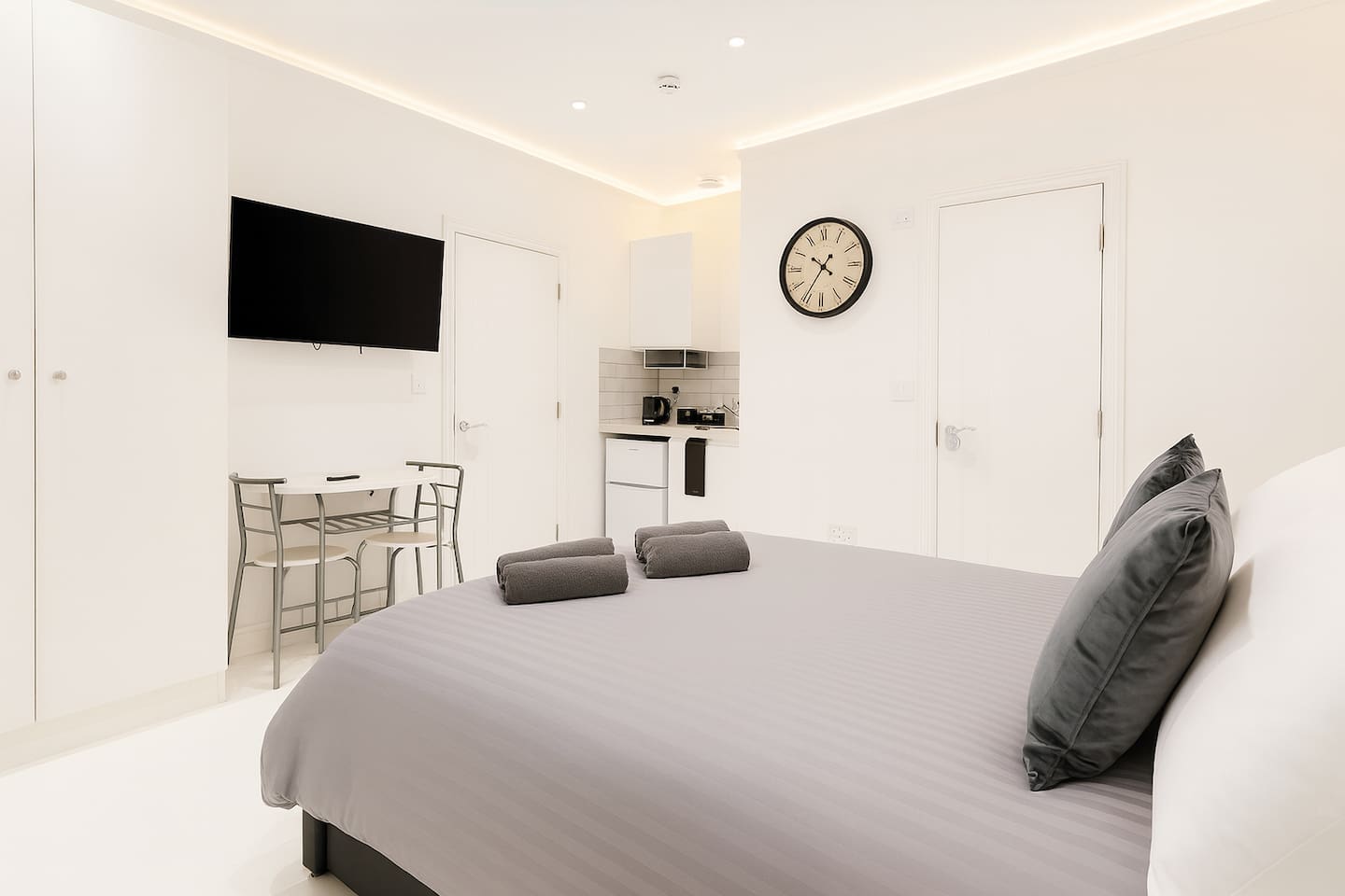 Contemporary open-plan studio with a comfy bed, dining area, and smart TV.