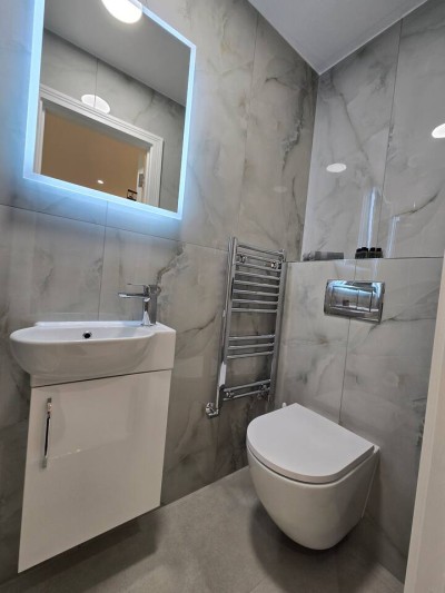 Chic, marble-tiled bathroom featuring an LED mirror and heated towel rail.