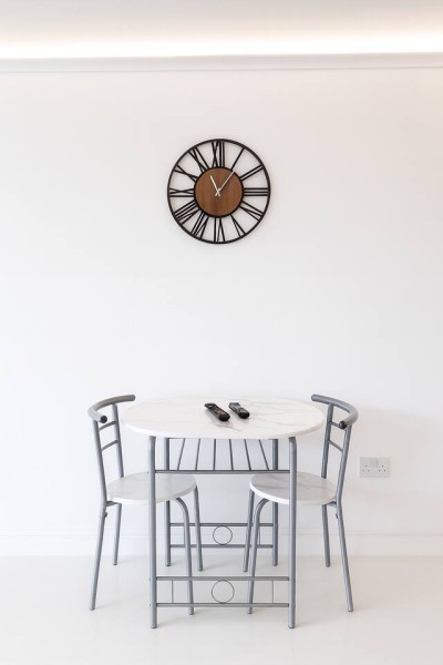 Minimal dining nook with cozy seating, modern clock, and bright clean style.
