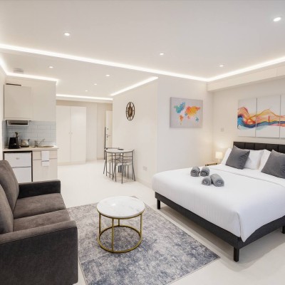 Modern studio with cozy bed, sofa, and kitchenette—bright, stylish, and functional.