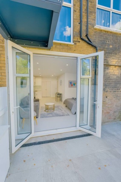 Open studio with glass doors, cozy sofa, and bright indoor-outdoor living.