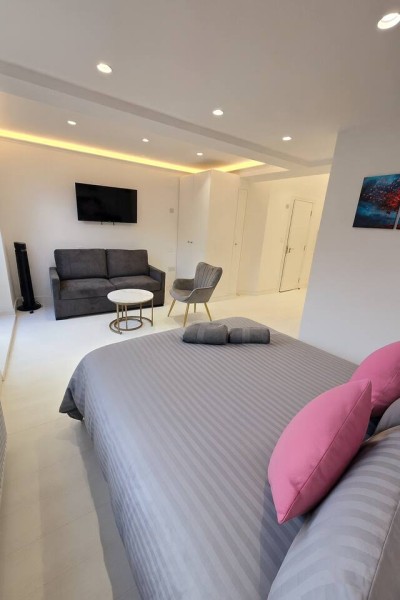 Modern studio with a cozy sofa, smart TV, and king bed for a relaxing stay.