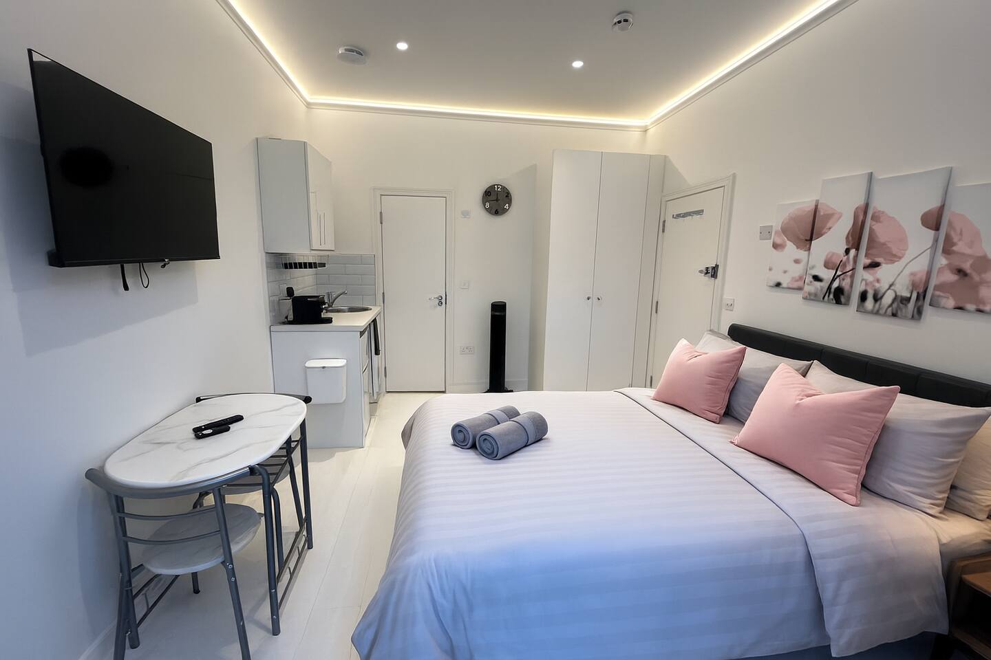 Modern studio with cozy bed, kitchenette, and floral accents for a stylish stay.