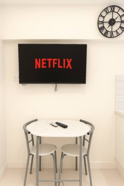 Cozy dining nook with Netflix-ready TV, modern clock, and compact seating.