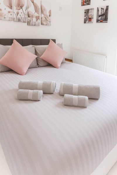 Cozy bedroom with floral art, striped bedding, and neatly arranged fresh towels.