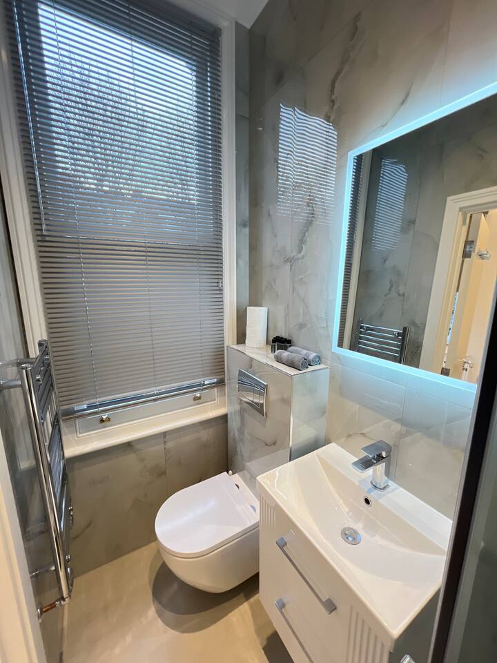 Elegant marble bathroom with vanity, LED mirror, and sleek modern finishes.