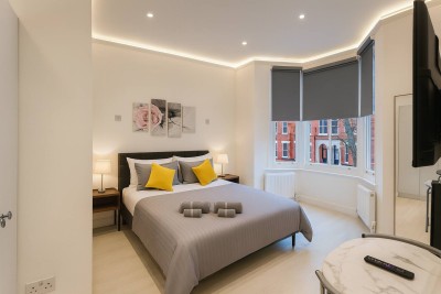 Bright bedroom with yellow accents, rose wall art, and cozy modern ambiance.