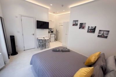 Stylish studio with grey bedding, Paris wall art, kitchenette, and cozy dining area.