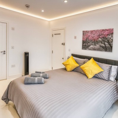 Modern bedroom with grey bedding, yellow accents, and warm lighting for cozy stays.