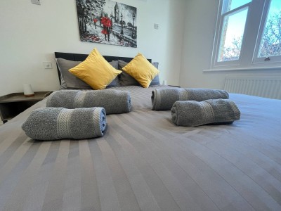 Cozy bedroom with grey bedding, yellow pillows, lamps, and vibrant red umbrella art.