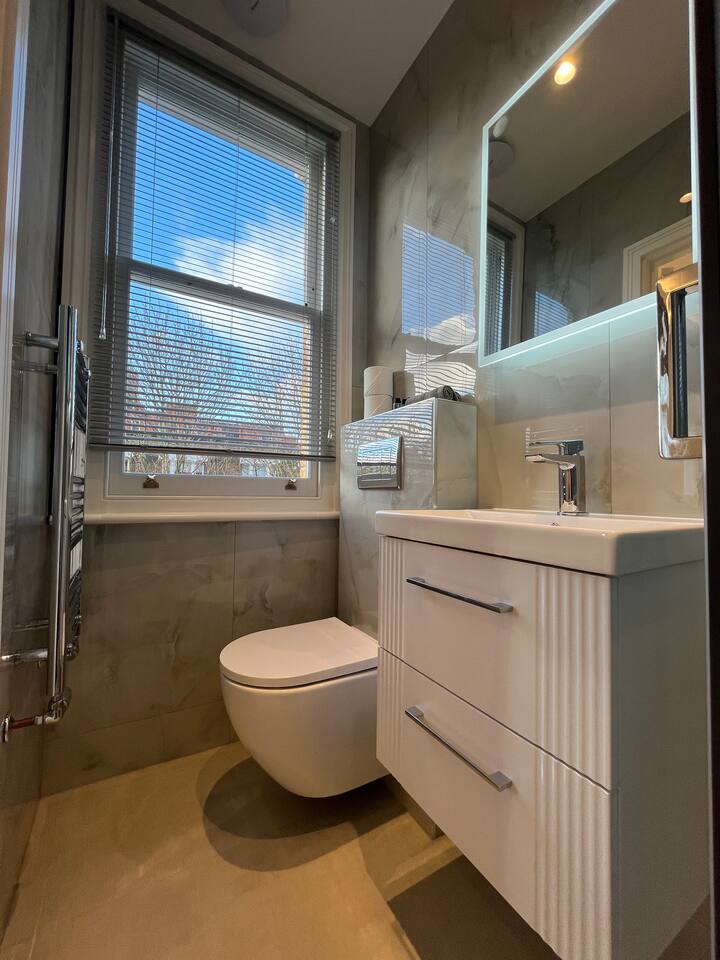 Stylish marble bathroom with LED mirror, vanity, and wall-mounted toilet design.
