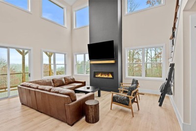 Gather in the soaring living room with floor‑to‑ceiling windows and a dramatic black fireplace. Sink into the plush leather sectional and enjoy views of the Blue Ridge after hiking, biking, or tubing the nearby New River.