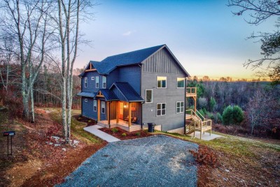 Arrive to this striking blue mountain retreat, where warm lights glow through gabled windows and a gravel drive leads to inviting porches. Nestled on a wooded hillside near Boone and the New River, it’s a serene base after your mountain adventures.