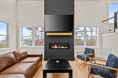 Gather in the spacious living room featuring a modern black fireplace, vaulted ceilings, and large windows that frame the mountain scenery. Relax on comfy seating after hiking Deep Gap trails or exploring Boone.