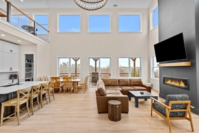 Enjoy the airy open-concept living space with soaring ceilings and a wall of windows. Gather on the plush sectional around the fireplace while family meals unfold at the adjacent dining table and chef’s kitchen—perfect for mountain getaways.