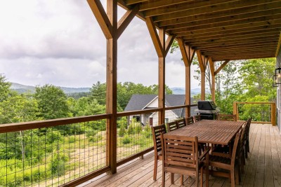 Dine alfresco on the covered deck with seating for your crew. Cable railings and timber posts frame lush forest and Blue Ridge views, making it the perfect spot for evening meals after exploring Boone and the New River.