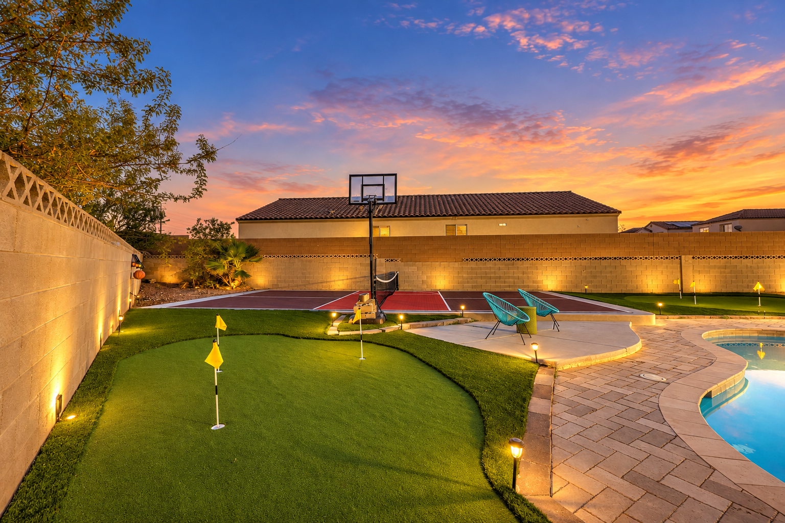 Resort-style backyard with pool, putting green & basketball at sunset