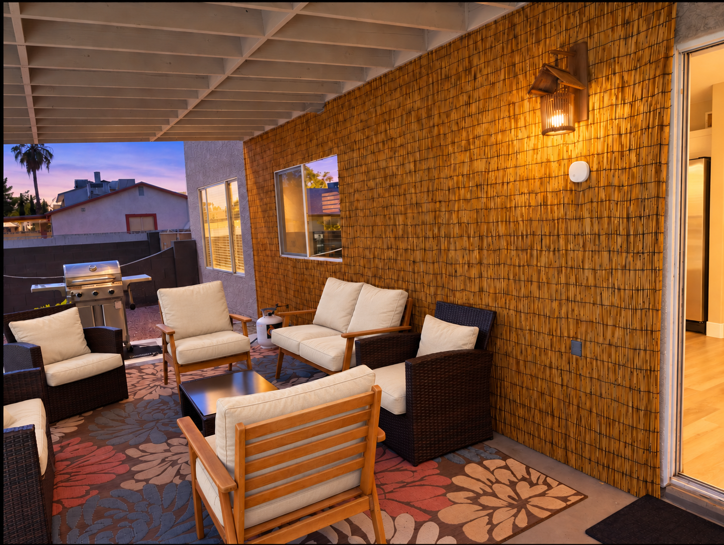 Cozy covered patio with lounge seating, warm lighting, and BBQ grill