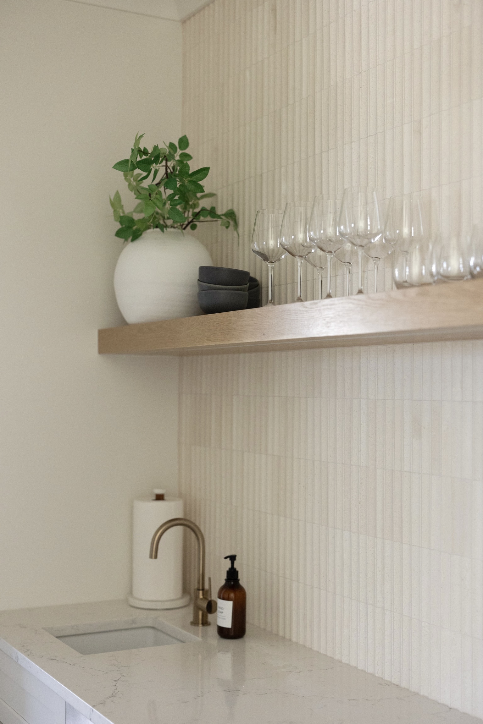 A wet bar with a quartz top and stocked wine glasses