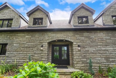 Admire the stately stone facade and charming dormer windows as you step up to the grand front entrance. This elegant exterior hints at the modern rustic comfort awaiting inside the cabin.