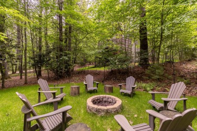 Unwind in the secluded backyard with a ring of Adirondack chairs around the stone fire pit—perfect for roasting s’mores and sharing laughs beneath the towering trees.