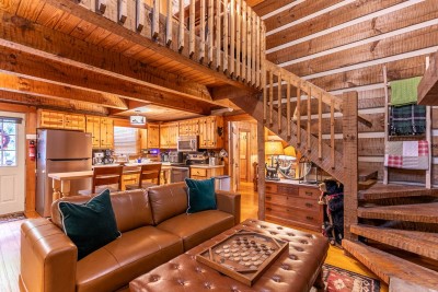 Settle into the comfy leather sofa with forest-green pillows under exposed beams while chatting with loved ones in the adjacent kitchen and watching the open staircase lead up to the loft.