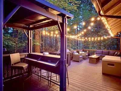 Forest-view deck with string lights, fire table & cozy lounge seating