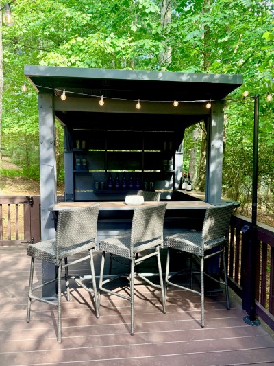Covered outdoor bar with string lights and forest views
