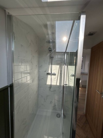 Stylish shower with skylight, subway tiles, and dual-head setup.