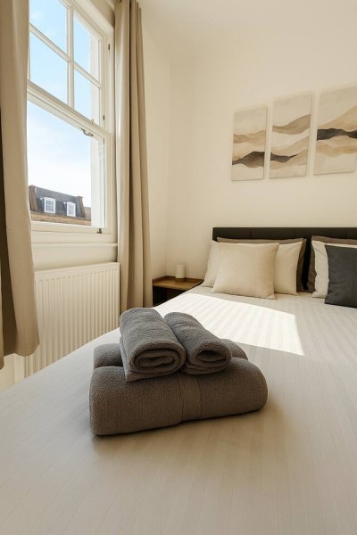 Bright guest-ready room with soft art, plush pillows, and folded towels.