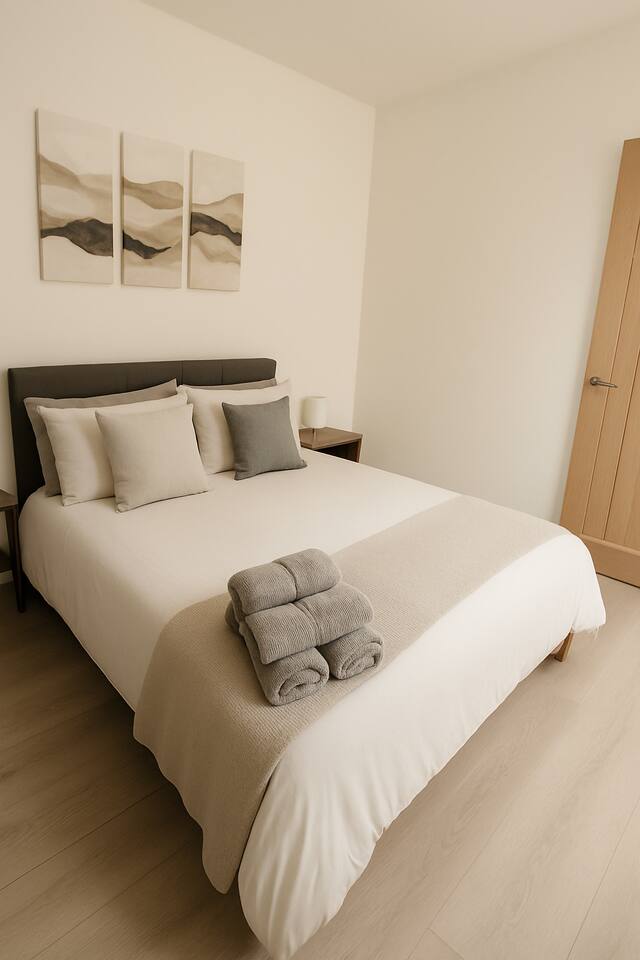 Neutral-toned bedroom with folded towels, soft lighting, and clean lines.